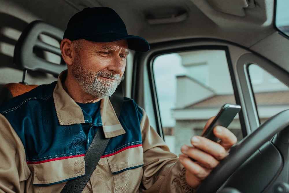 Mand ser på telefon i bilen.